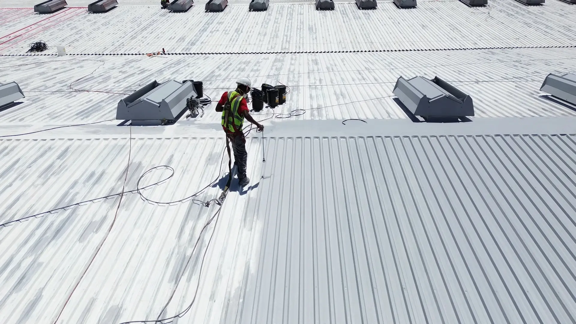 Worker applying roof coatings on commercial roof
